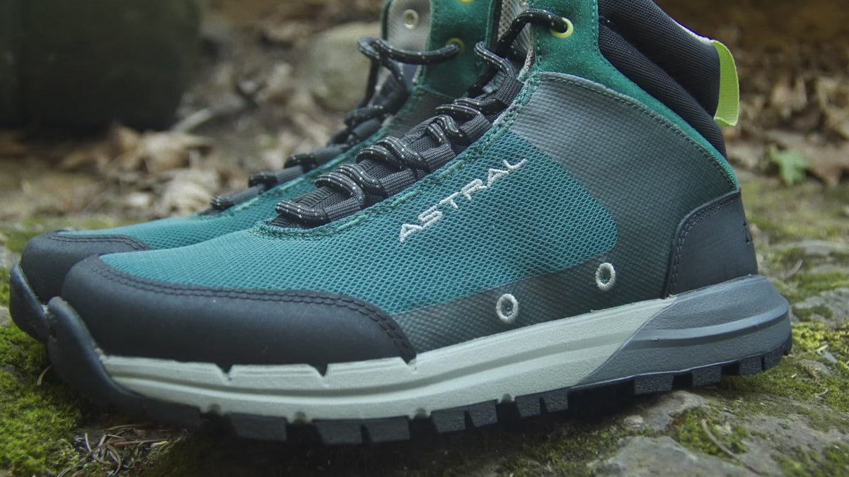 Astral Tr1 Merge hiking boots in green and black on mossy ground, showing detail of the shoe's side and sole.